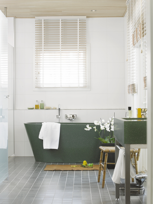 Kylpyhuoneen amme ja allaskaluste jatkavat asunnon muiden pintojen vihreää värisävyteemaa.