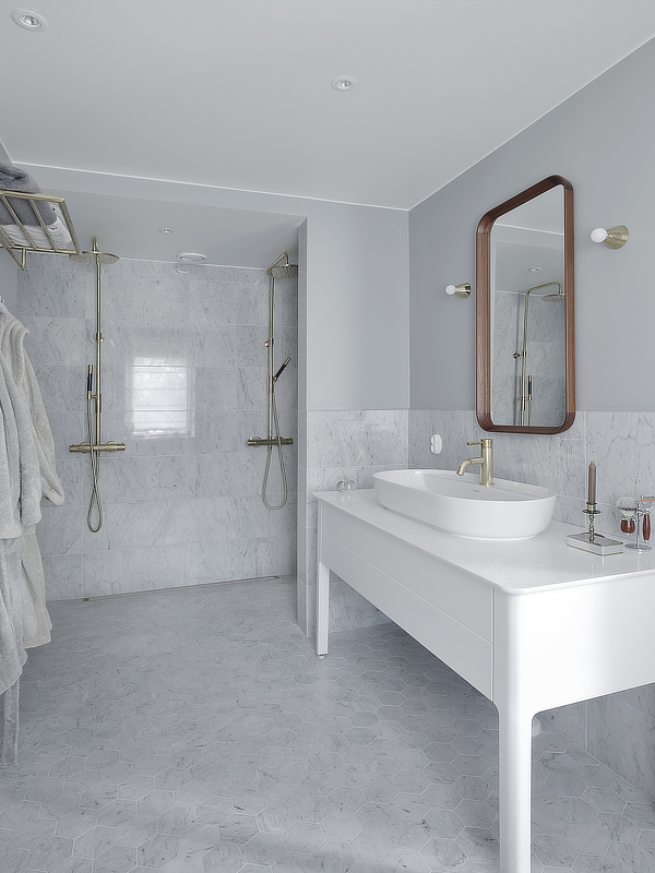Karihtalan suunnittelemassa helsinkiläisen omakotitalon remontissa uusittu vaalea kylpyhuone kauniilla allaskalusteella ja sisustuspeilillä.