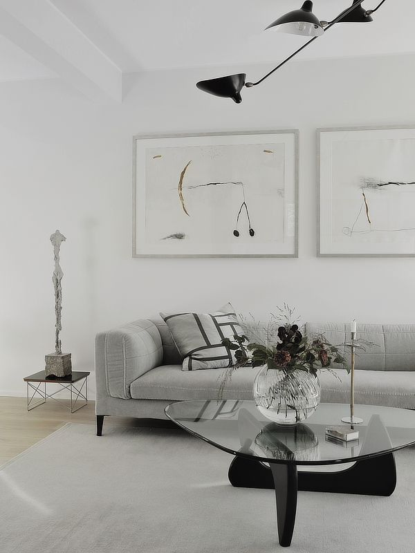 Sisustus jossa on moderni sohva ja lasinen sohvapöytä sekä taidetta.