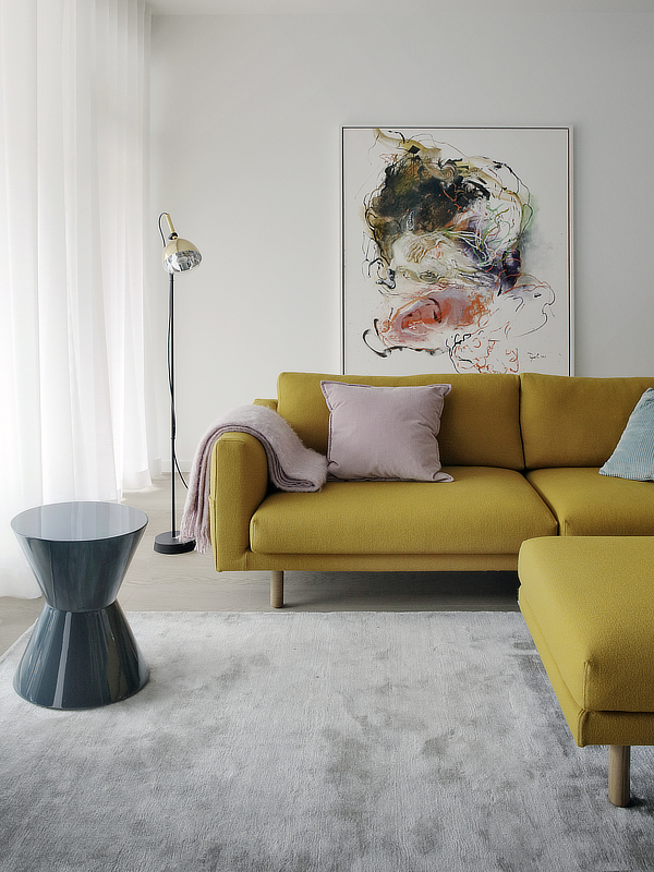 Kerrostaloasunnon sisustus rakentui vanhan keltaisen sohvan ja taulujen värimaailman ympärille.